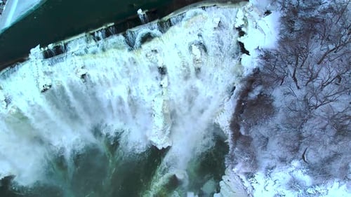 atemberaubende Luftaufnahme eines riesigen Wasserfalls im Winter mit tosendem Wasser, das dabei von oben herabstürzt