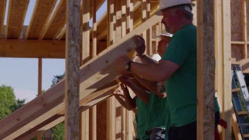 Team of Volunteers Building Structure Outdoors on Sunny Day