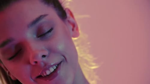 Jeune femme posant et souriant sur fond blanc avec des lumières colorées