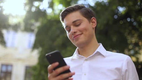 Frame From Below Smile Face Successful Business Man Use Phone on City Sunset District Street Mobile