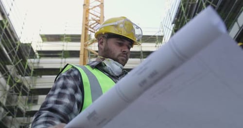 Construction Worker Reviews Plans at Building Site