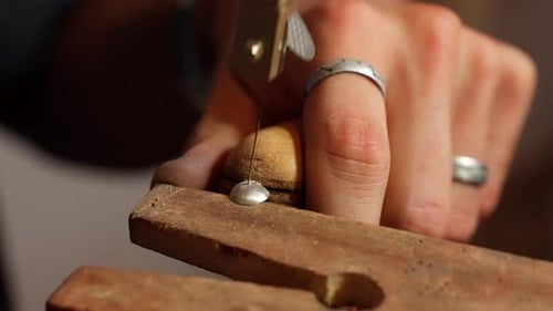 Man sawing through a metal object with precision in a workshop.