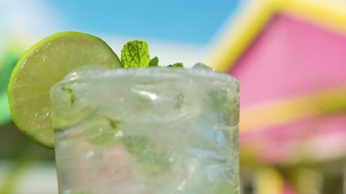White rum is added to fresh mojito, shallow depth of field of tropical pink home background