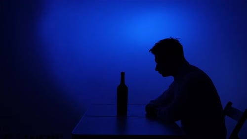 Lonely man sitting with wine in dark room