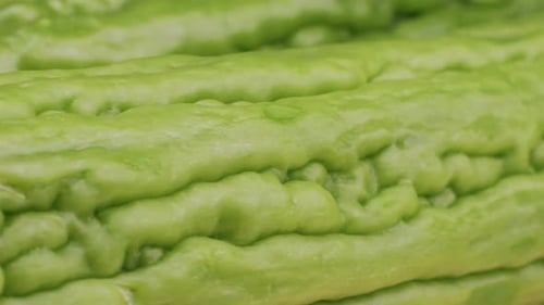 Une gourde amère, un légume souvent utilisé comme ingrédient en cuisine, est posée sur une table en bois.
