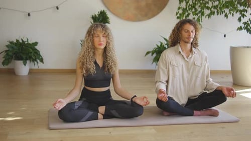 Couple Meditating in Yoga Position in a Bright Studio