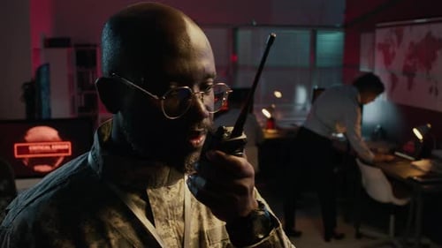 Male Military Officer Calling for Support on Radio during Command Center Attack