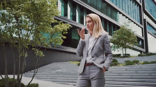 Woman Holding Phone and Recording Voice Message on Street