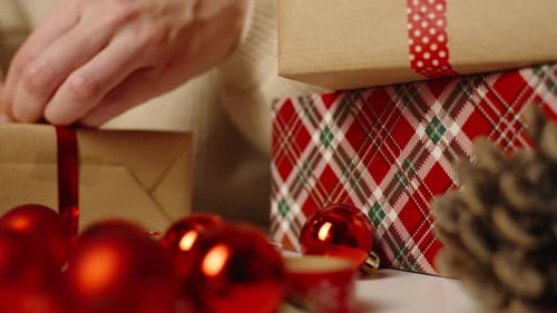 Woman Wrapping Christmas Presents with Red Ribbon
