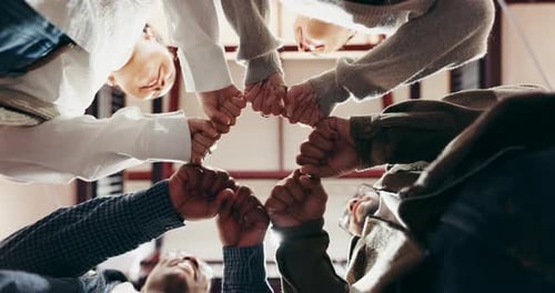 Hands, students and fist bump in circle at college, low angle and support for motivation for goals