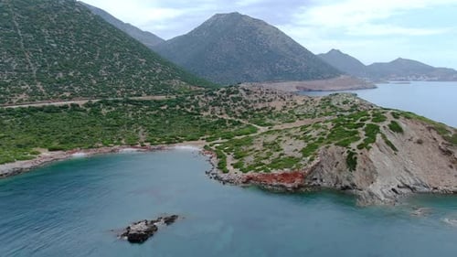 Mediterranean coastal landscape with green bushes and mountains in the background. Drone panoramic v