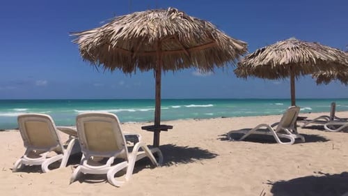Sand beach and straw umbrellas in Varadero, Cuba with sunbeds and blue ocean