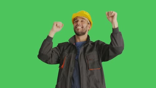 Mid Shot of a Worker Wearing Hard Hat Dancing and Raising His Hands. Background is Green Screen.