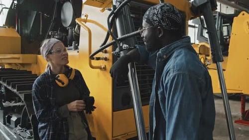 Workers Talking Next to Large Yellow Machine
