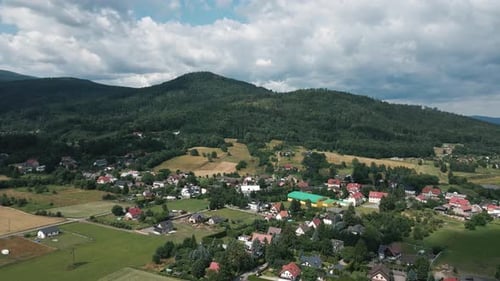 Aerial view of rural village and green valley near mountain range in summer