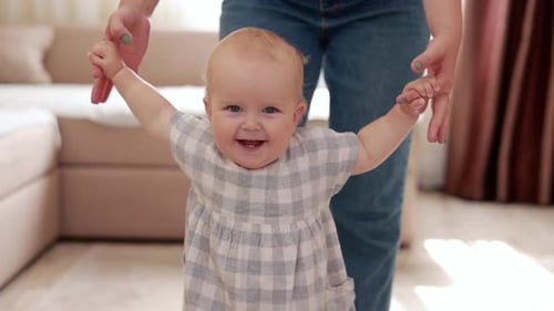 smiling baby boy girl learning to walk with mom, taking first steps with mother helping infant, teac