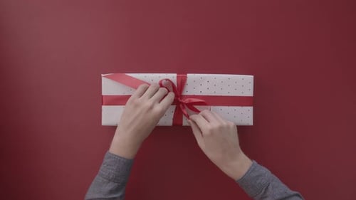 Hands Untie Red Ribbon on Beautiful Gift