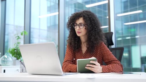 Woman working at desk with laptop and tablet