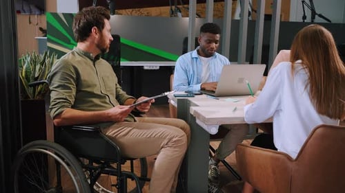 Young Manager in Wheelchair Conducts Meeting in Office