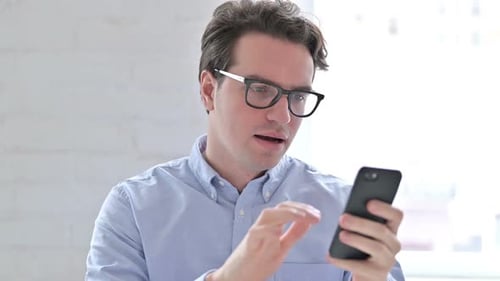 Man Celebrates Using Smartphone Indoors