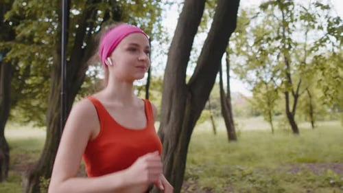 Athletic Fitness Sport Runner Woman Training Marathon Run Listening Music in Earphones in Park