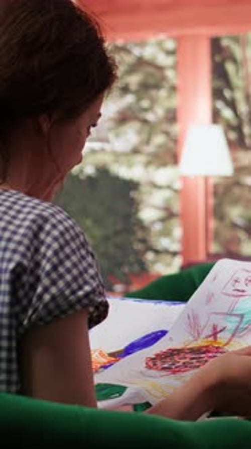 Woman Looking at Colorful Child's Drawing Indoors