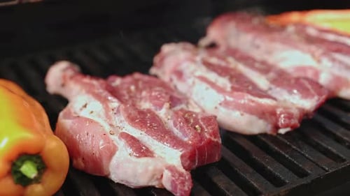 Saftiges Steak mit Gewürzen und Kräutern, Flammen und sich langsam bewegendem Rauch braten
