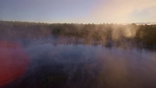 Aerial drone view of mist floating upward from the water at sunrise.