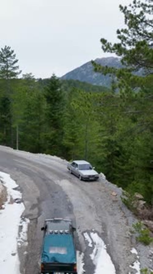 Vertical Video Winter Forest Serenity Aerial View of Pickup Truck on Snowy Road Surrounded By