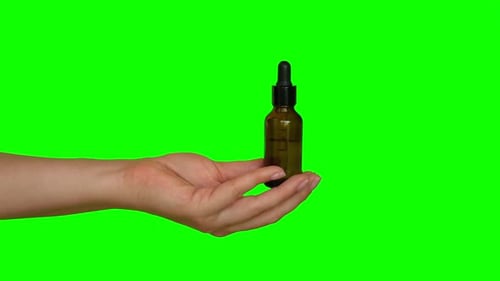 Female Hands Testing Natural Oil Cosmetics on a Chroma Green Screen Background Dropper Glass Bottle