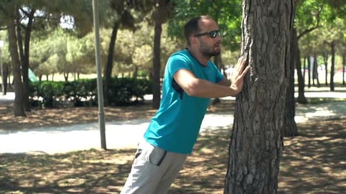 Man Doing Push-Ups On Tree Trunk In City Park