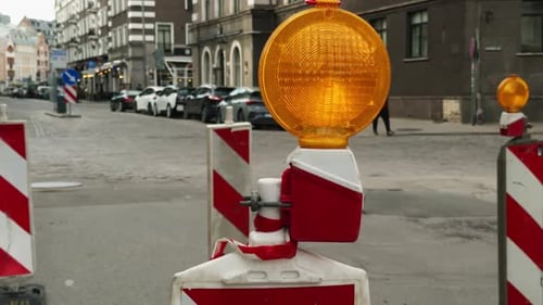 A Yellow Lighting Sits on a Red and White Barrier By the Road