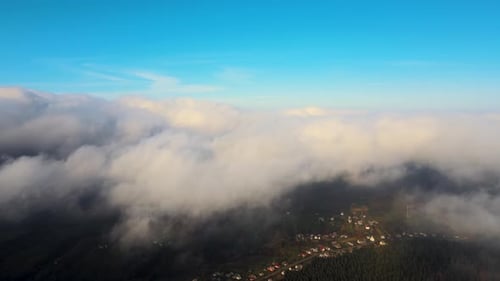 View From Above of Vibrant Landscape of Foggy Clouds Covering Mountain Hills and Village Houses at