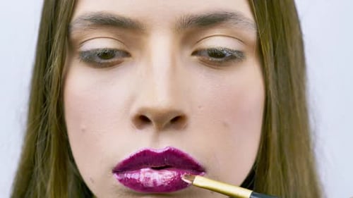 Woman Applying Magenta Lip Gloss with Brush, Close Up