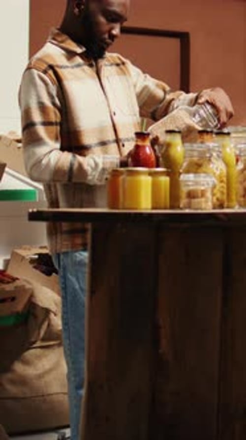 Young Adult Man Filling Jars with Food