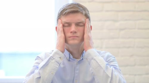 Young Adult Man Rubbing Temples with Headache