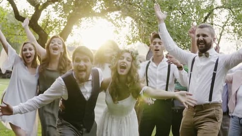Cheerful wedding party dancing outdoors at sunset