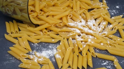 Close-up of Raw Penne Pasta and Flour