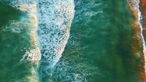 Zumbido: olas turquesas del océano que bañan una playa de arena con turistas caminantes desconocidos