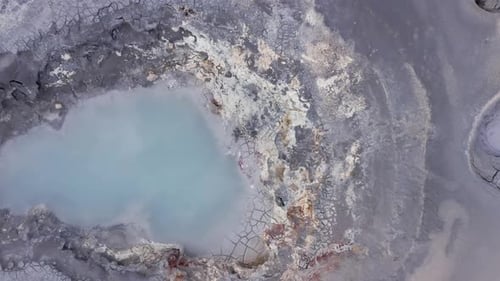 Above large active mudpot in Iceland, vapor rising from hole, volcanic