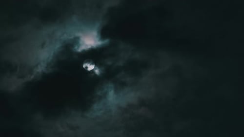 Full Moon behind Thick Dark Clouds at Night