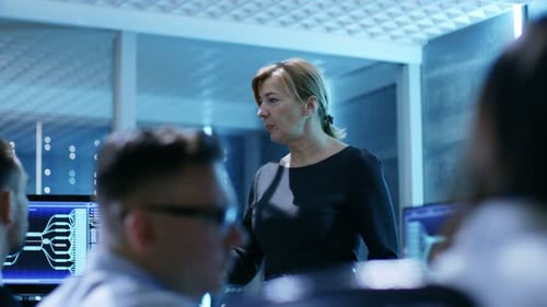 Una supervisora dirige una sesión informativa para sus empleados en la Agencia de Vigilancia del Gobierno. La habitación es divertida