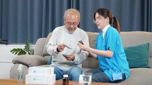 Woman Nurse Caregiver Show Prescription Drug to Senior Man at Nursing Home