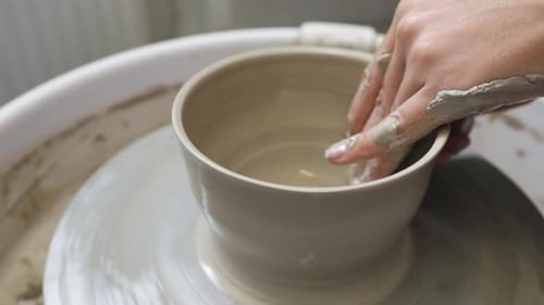 Artist in the pottery studio making bowl with her hands, handmade creative artist