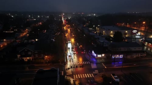 Rainy and cloudy night in small american town. Cars on junction with orange lighting lanterns. Aeria