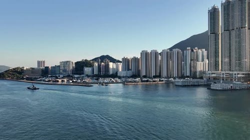 Tall buildings line the shore of Hong Kong. Mountains and landscape with skyscrapers in the urban to