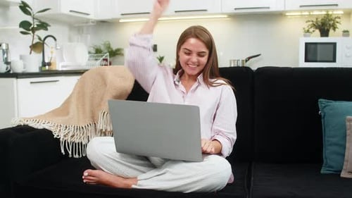 Excited Woman Celebrating Good News on Laptop at Home