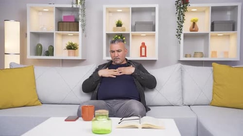 Man Sitting on Couch Experiencing Discomfort