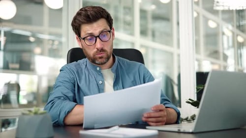 Adult Reads Paper Documents in Modern Office