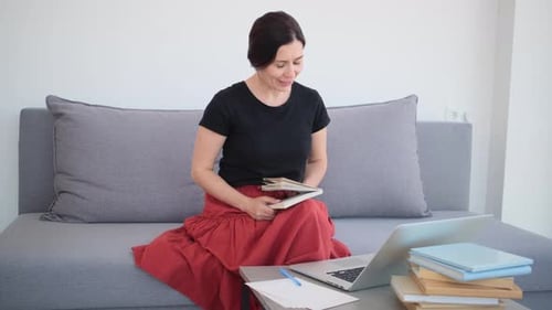 Woman On Couch Video Conferencing and Reading Book